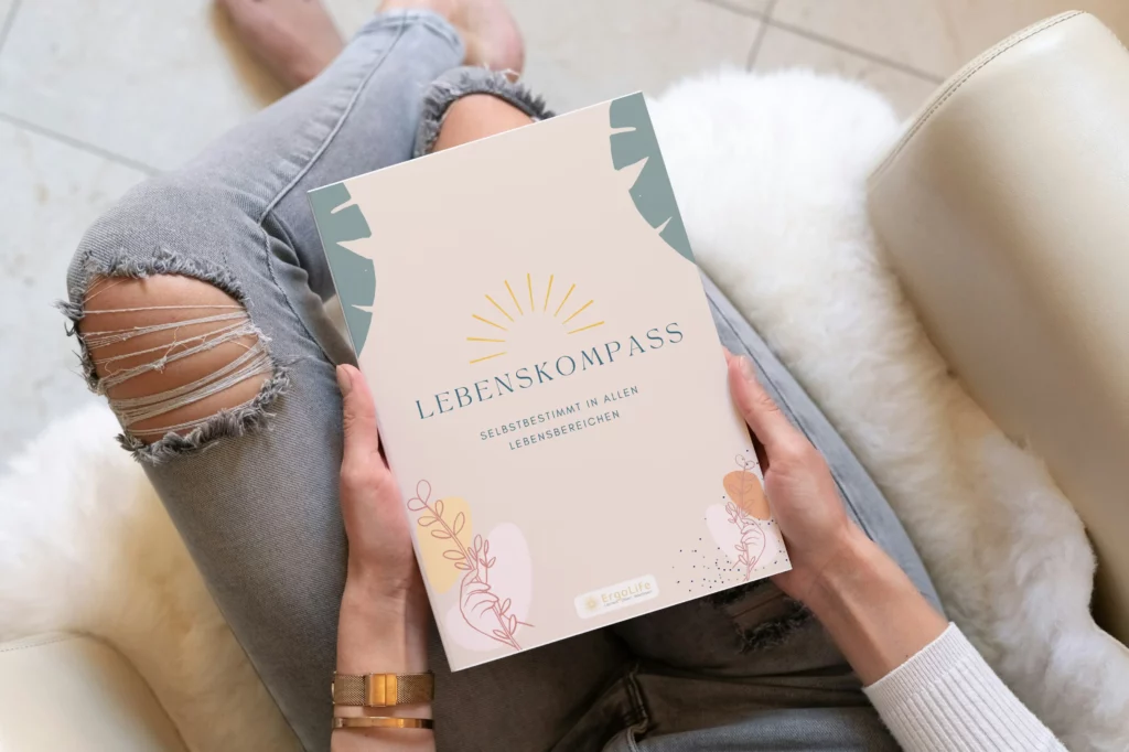 Hände halten das Heft „Lebenskompass“ auf dem Schoß
