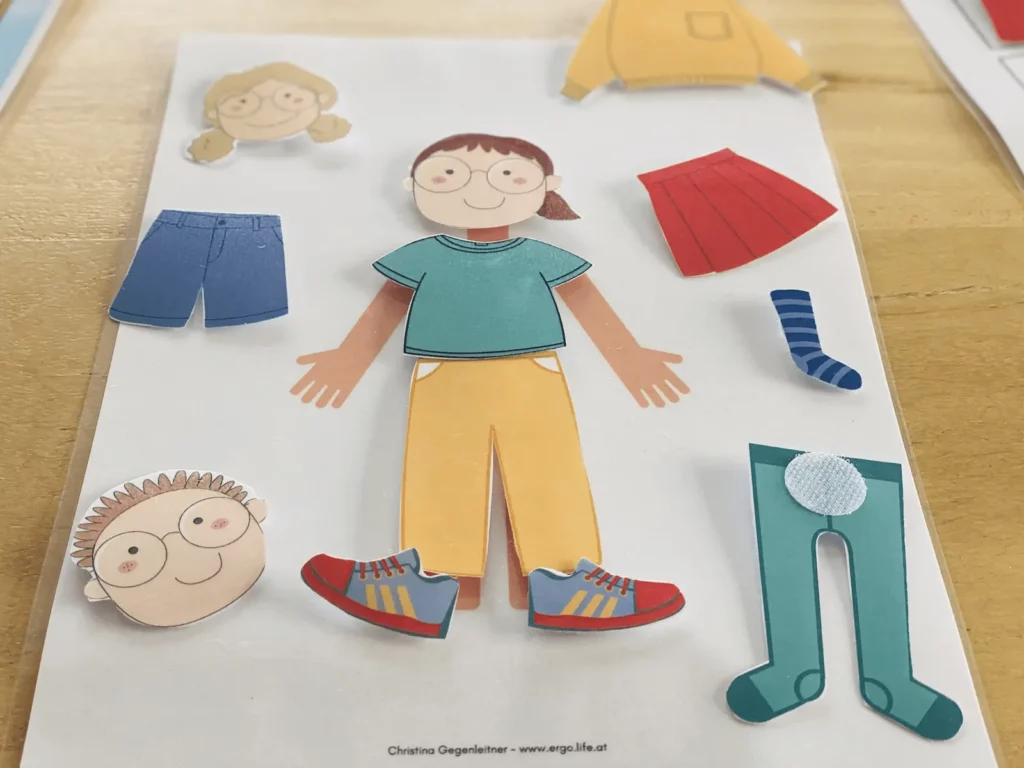 Anziehpuppe aus Papier mit ausgeschnittenen Kleidungsstücken