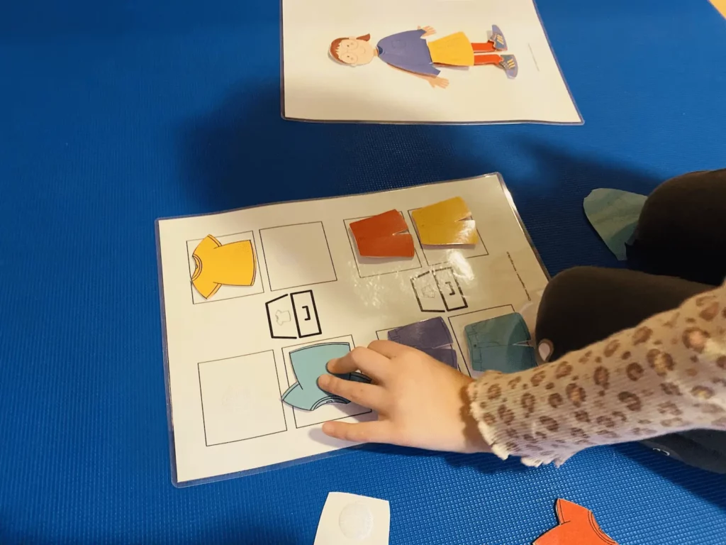 Kind legt in der TEACCH-Aufgabenmappe Kleidungskarten an die richtige Stelle