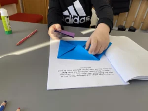 Kind faltet ein blaues Papier nach Anleitung