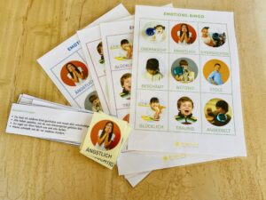 Ausgedrucktes Emotions-Bingo mit echten Fotos auf einem Holztisch