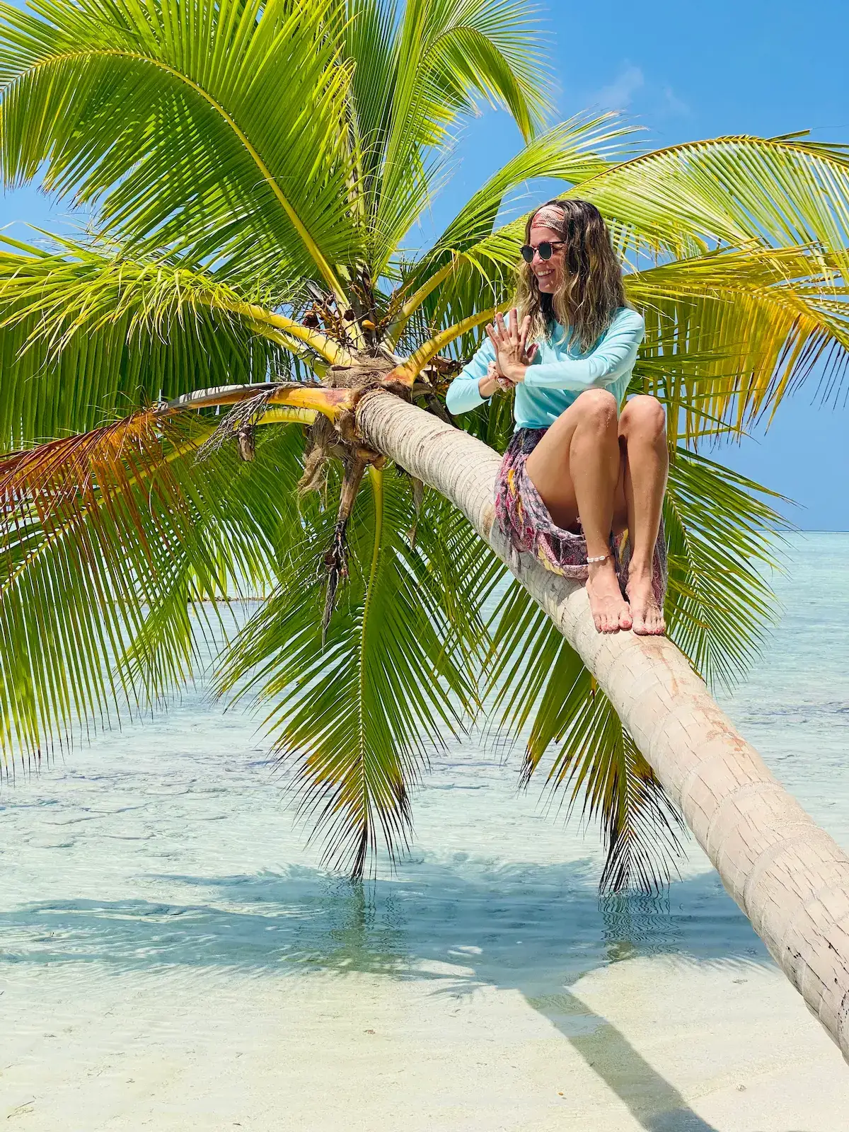 Christina Gegenleitner sitzt auf einer schrägen Palme über dem Meer