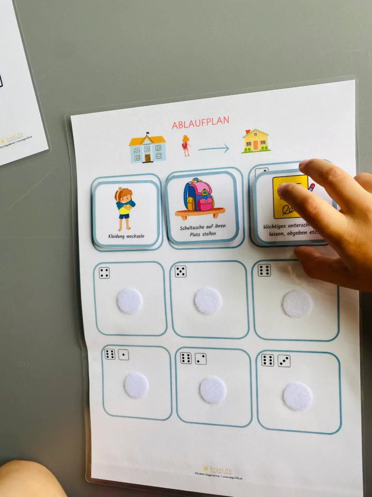 Kinderhand legt eine Bildkarte auf einen Ablaufplan aus dem Schulstarthelfer