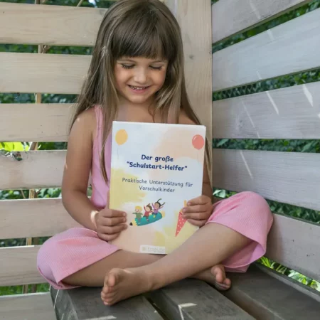 Mädchen sitzt auf einer Bank und liest im großen Schulstarthelfer