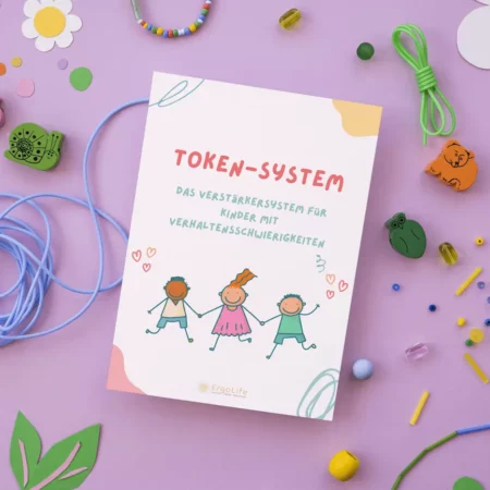 Heft „Token-System“ auf lila Hintergrund mit Bastelmaterial